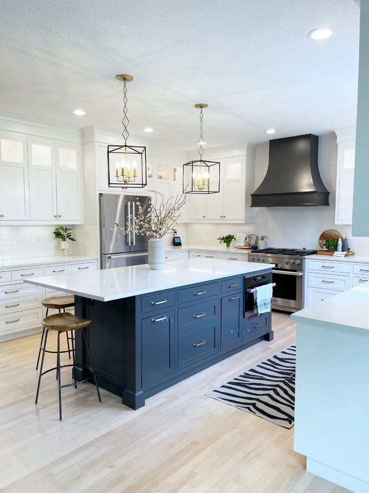 a kitchen with white cabinets and blue island