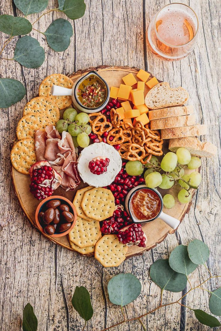 a wooden platter filled with cheese, crackers and fruit