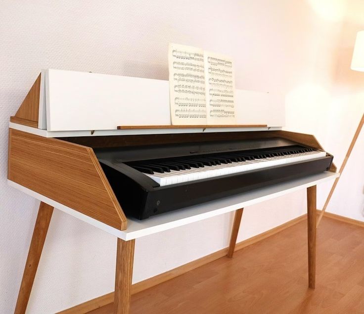 a black and white piano sitting on top of a wooden table next to a lamp