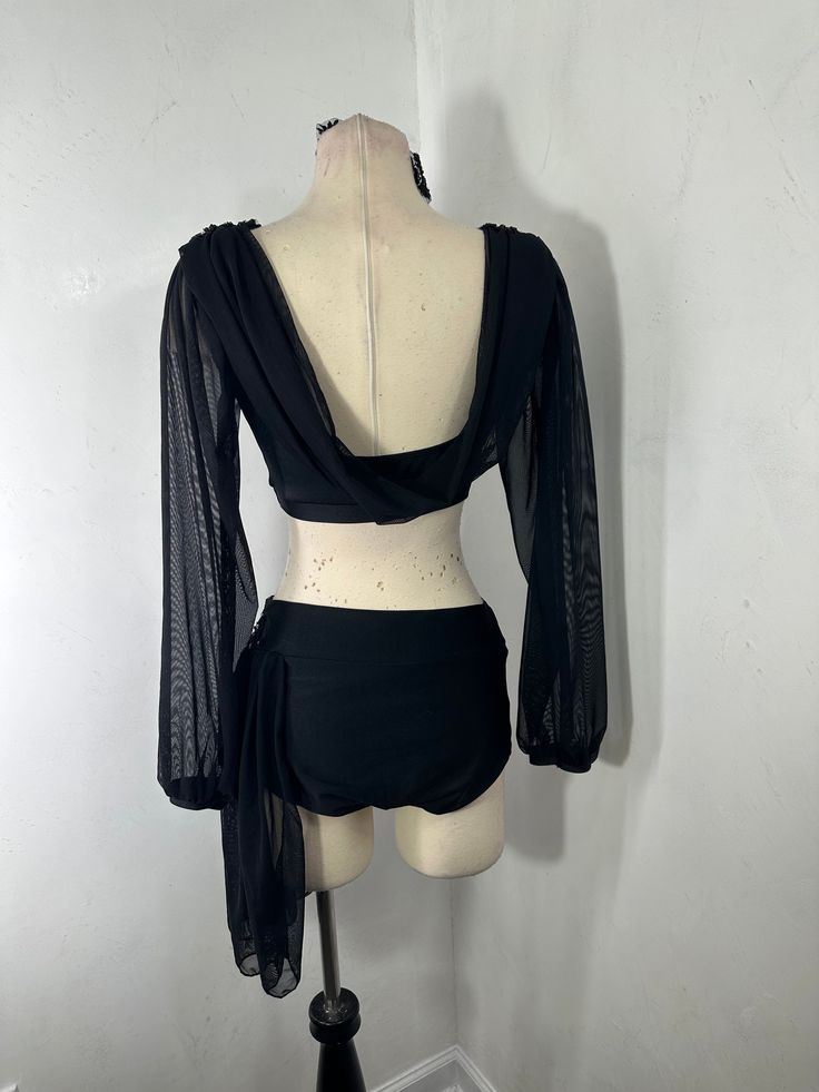 a mannequin wearing a black top with sheer sleeves