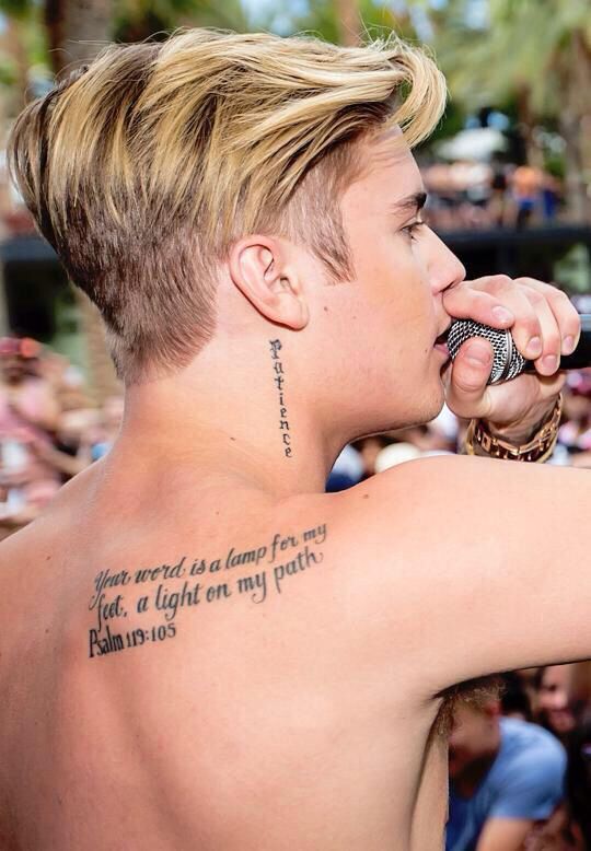 a man with tattoos on his chest holding a microphone in front of a large crowd