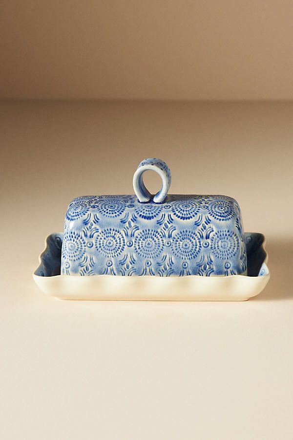 a blue and white dish with a ring on it's handle sitting on a plate