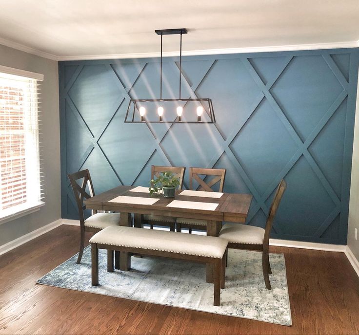 a dining room with blue walls and wooden flooring is pictured in this image, there are four chairs around the table