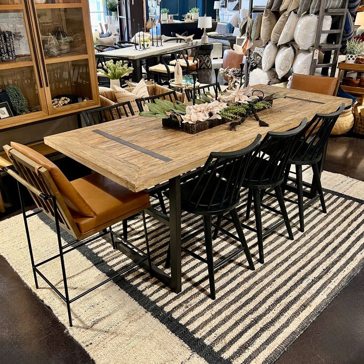 a dining room table surrounded by chairs and rugs in front of a store display