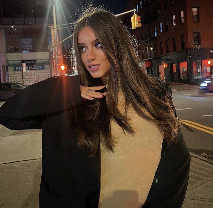 a woman is standing on the street at night