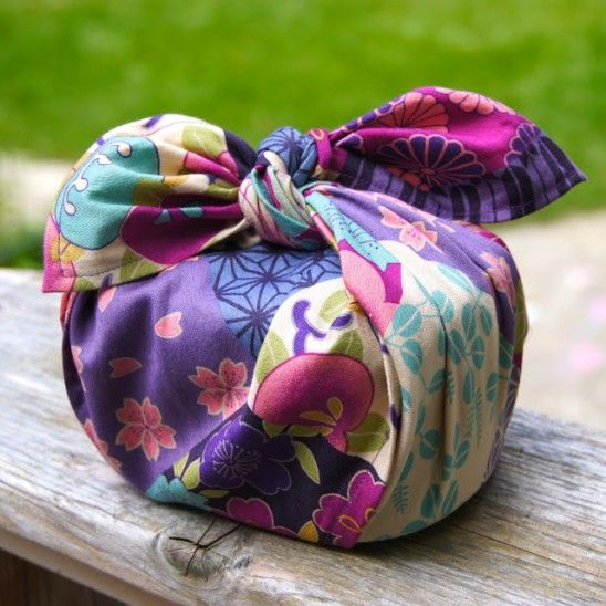 a colorful flowered bag sitting on top of a wooden bench next to a green field