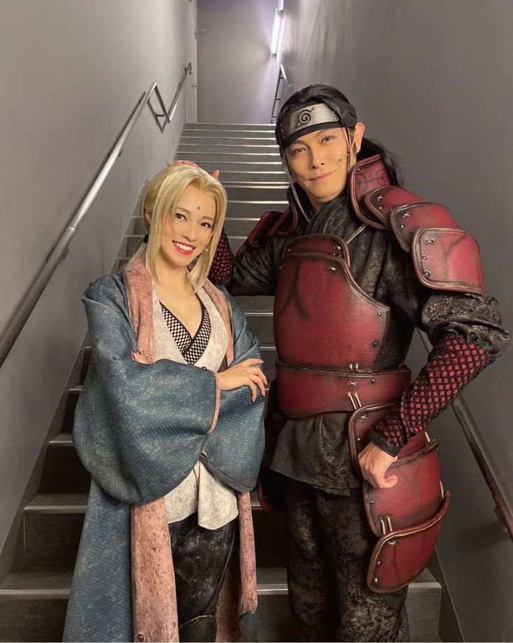 a man and woman dressed in medieval costumes standing on the stairs with their arms around each other