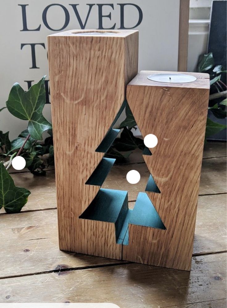 a wooden block with a cut out christmas tree in the center and some lights around it