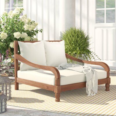 a wooden chair sitting on top of a rug next to flowers and potted plants