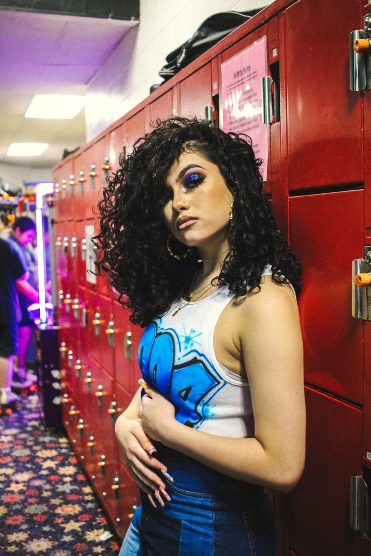 a woman standing in front of lockers with her hands on her hips and looking at the camera