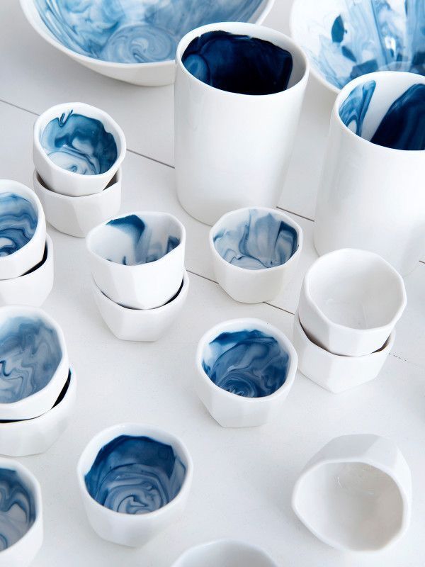 blue and white marbled bowls are arranged on a table with cups in the middle