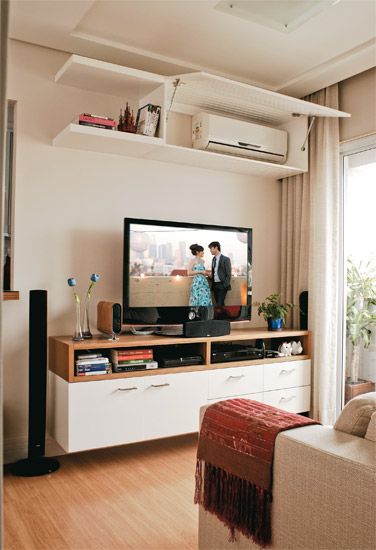 two people standing in front of a flat screen tv on top of a wooden entertainment center