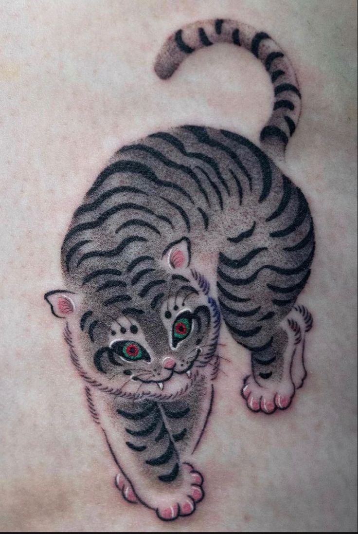 a small tiger cub tattoo on the back of a man's chest, with red eyes