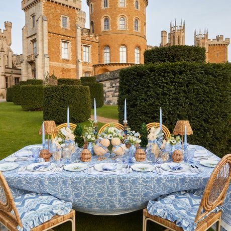 the table is set with blue and white linens for an elegant dinner in front of a castle