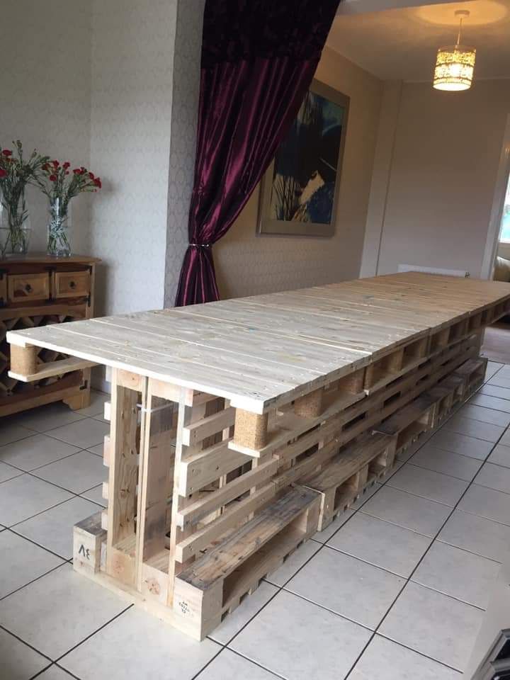 a table made out of wooden pallets sitting on top of a white tiled floor