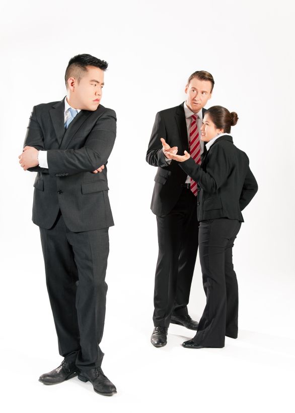 two men and a woman in business attire standing next to each other with their arms crossed