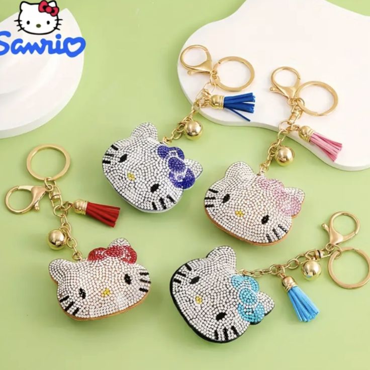 hello kitty keychains with tassels on them sitting on a green surface