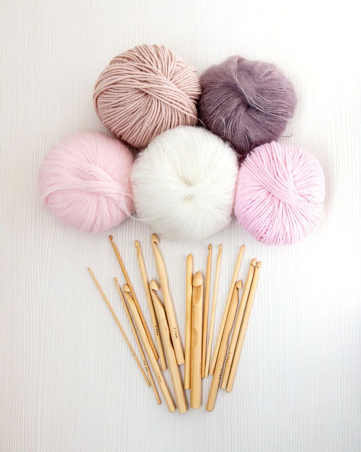 several skeins of yarn and knitting needles on a white surface