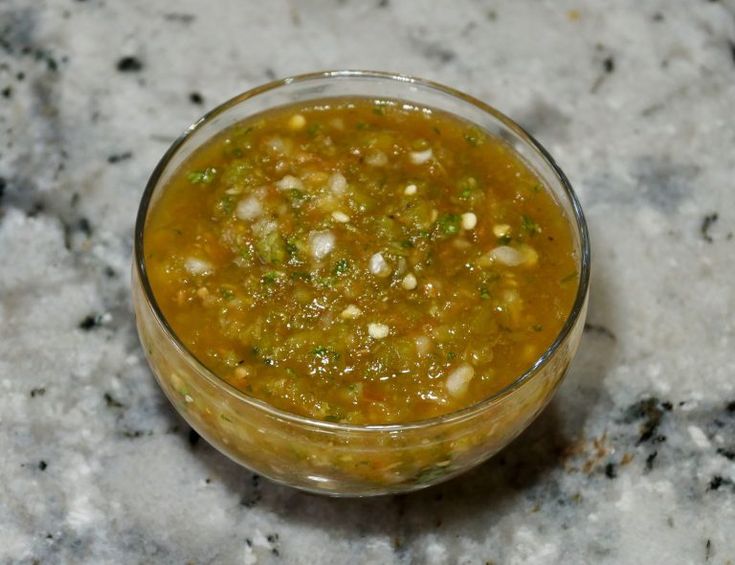 a small glass bowl filled with food on top of a counter next to a marble surface