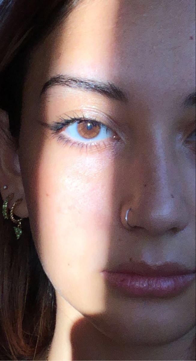 a close up of a woman with blue eyes and piercings on her ear,