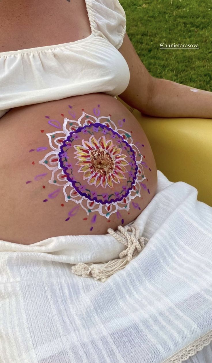 a pregnant woman's belly with an intricate design painted on the stomach and side