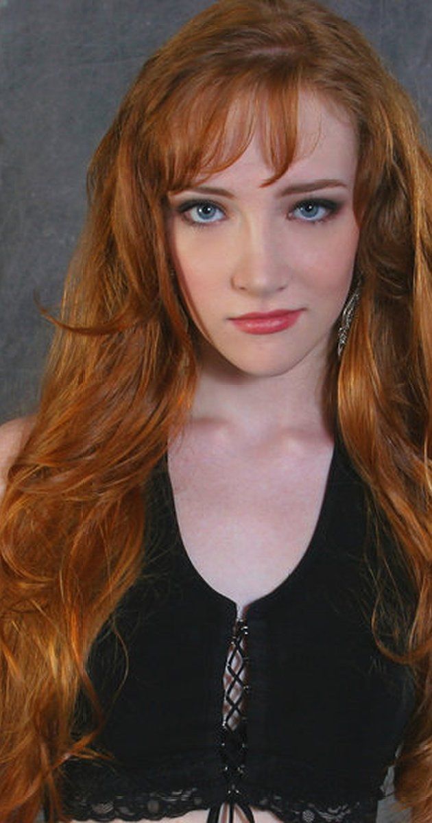 a woman with long red hair wearing a black top