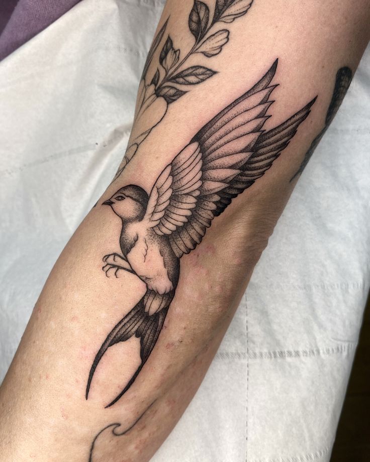 a tattoo on the arm of a person with a bird and flower in its beak