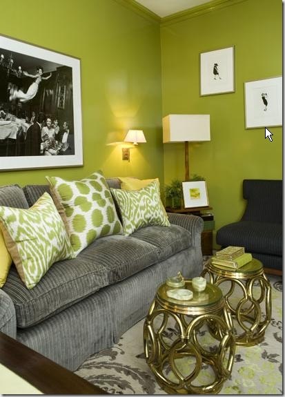 a living room with green walls and yellow pillows on the couches in front of a coffee table