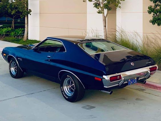 a blue muscle car parked in front of a building