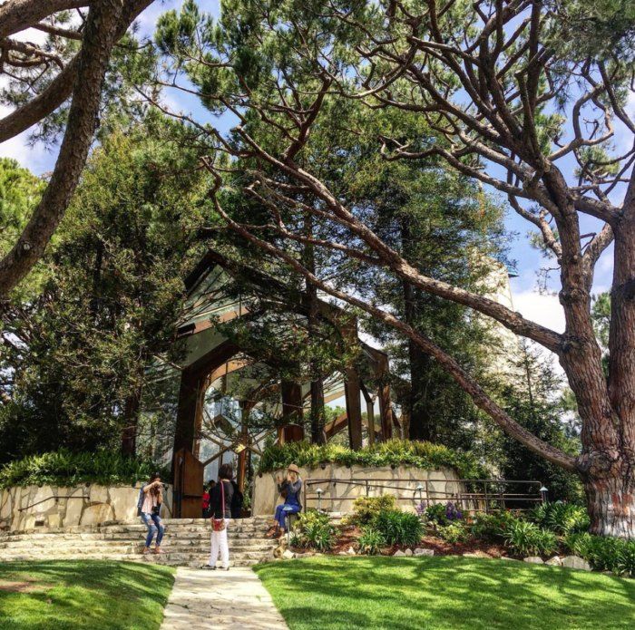 two people are standing on the steps in front of a building with trees around it