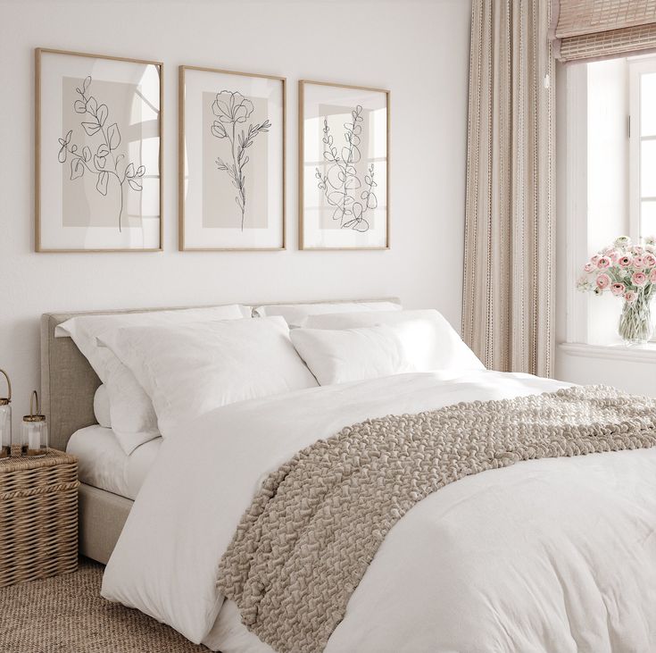 a bed with white sheets and pillows in a bedroom next to a window, framed pictures on the wall