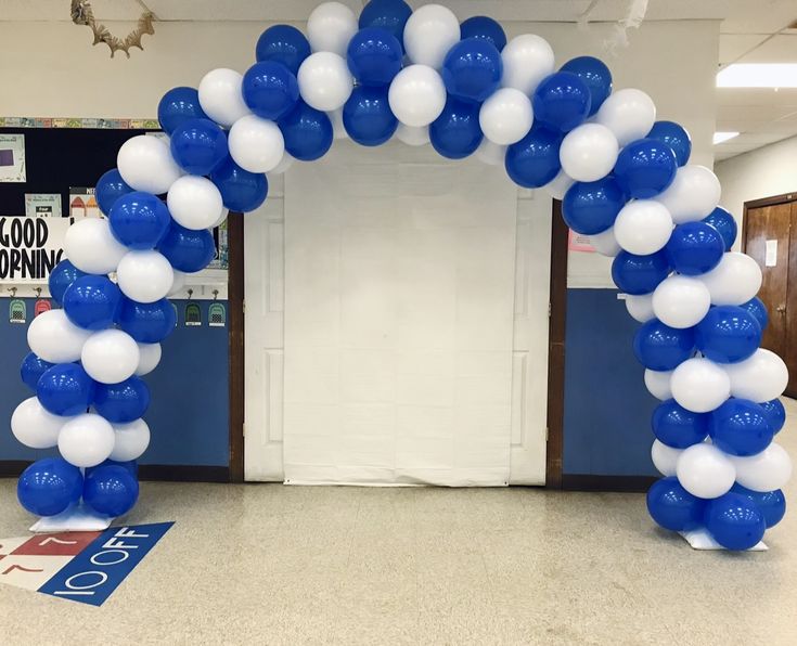 an arch made out of balloons is in the middle of a room with blue and white decorations