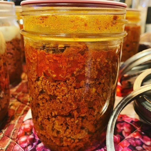 several jars filled with food sitting on top of a colorful table cloth next to utensils