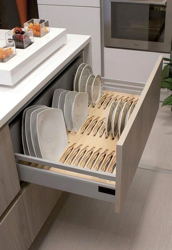 an open drawer in a kitchen filled with plates and silverware next to a counter