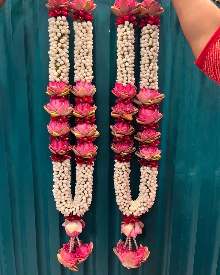 two rows of flowers are attached to the side of a blue wall with white beads