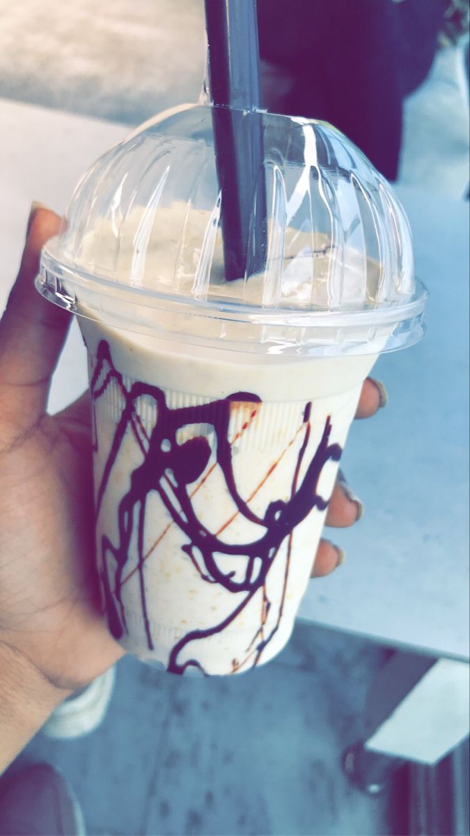 a person holding up a drink with chocolate on it