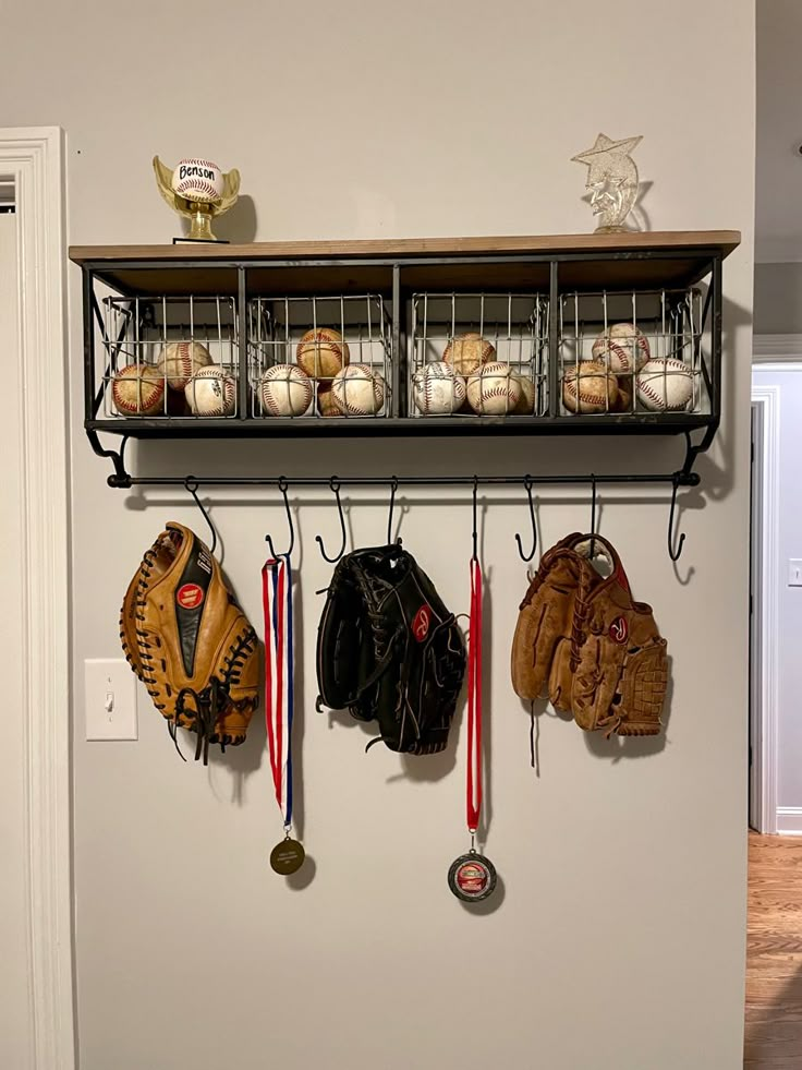 a wall mounted shelf filled with baseballs and mitts hanging from it's sides