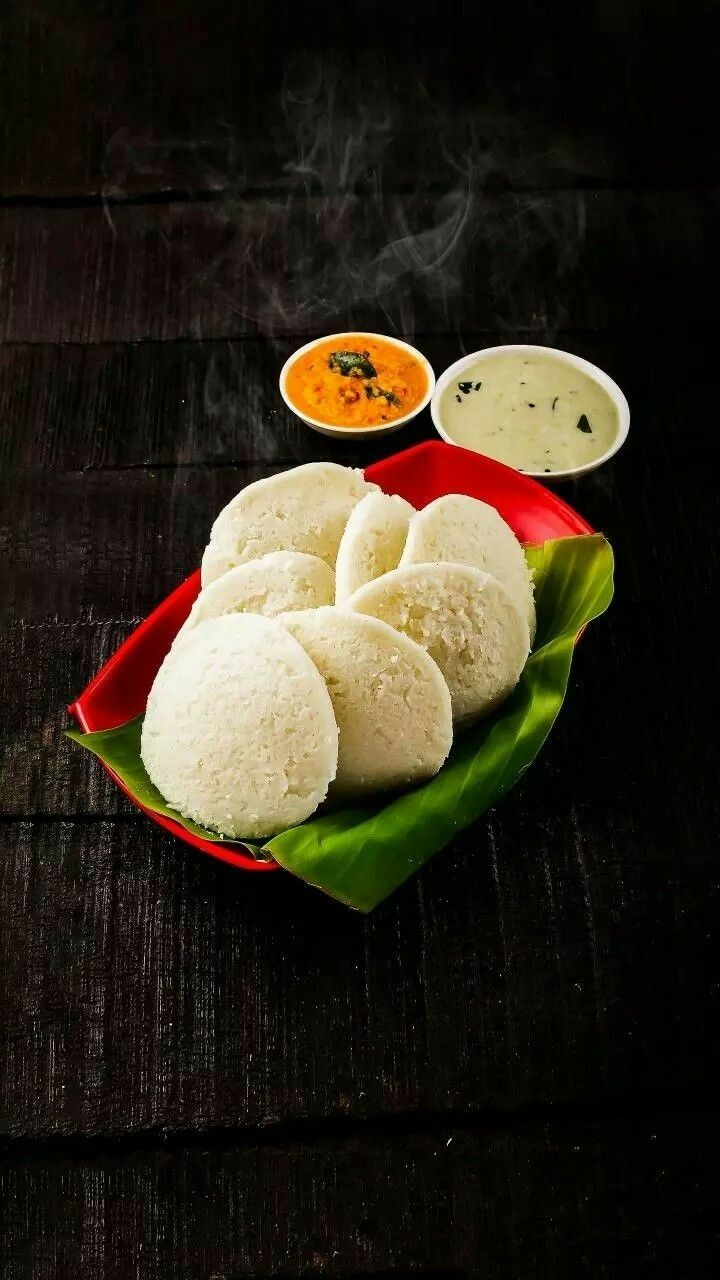 some food is sitting on a red plate with green leaves and sauces next to it