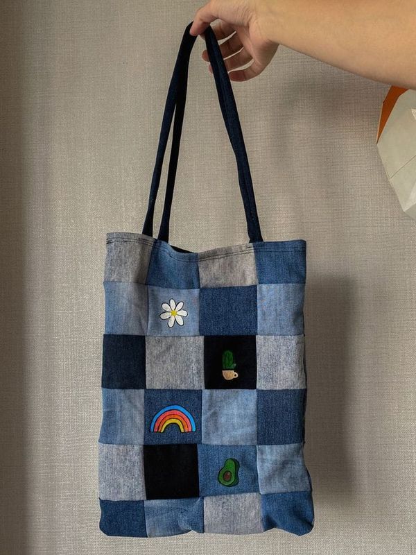 a hand holding a blue patchwork tote bag