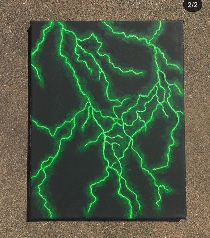 a square piece of artwork with green lightning bolts on black paper in front of it