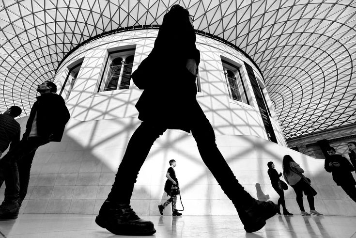 several people are walking around in a building with a glass ceiling and large round windows