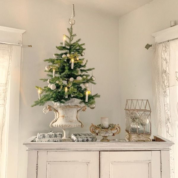 a small christmas tree is on top of an old cabinet in the corner of a room