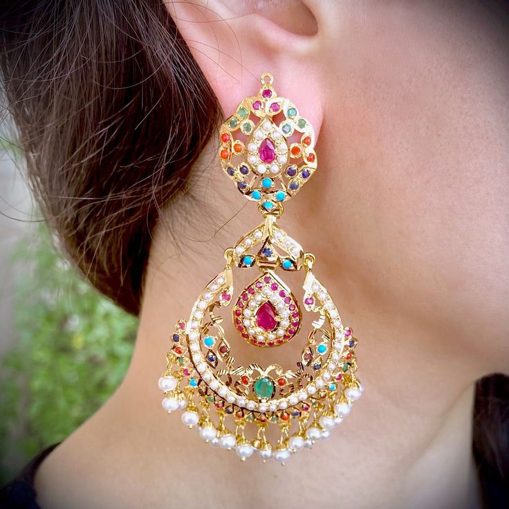 Featured is a pair of oversized chandbali / Brijbala earrings in 22k gold embellished with navratan color stones: rubies, emeralds, pearls, coral, turquoise (pheroza), sapphire and garnet. The earrings weigh 35.5 gms and are approx 3 inches in length. A perfect gift option under 2 lacs. Multicolor Temple Jewelry Chandbalis Drop Earrings, Multicolor Temple Jewelry Chandbalis, Multicolor Chandbalis With Intricate Temple Design, Multicolor Temple Jewelry Bridal Earrings With Intricate Design, Multicolor Chandbali Earrings With Intricate Design, 22k Gold Chandbali Earrings For Navratri, 22k Gold Chandbalis For Navratri, Multicolor Chandbali Bridal Earrings With Intricate Design, Multicolor Temple Jewelry Earrings With Latkans