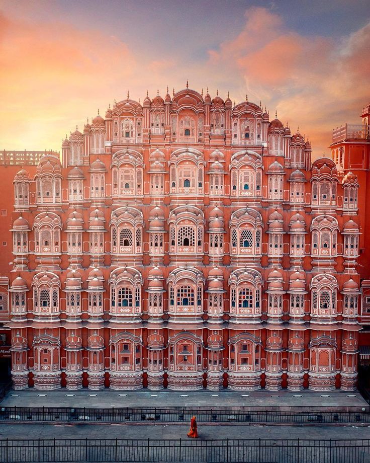 a large building with many windows on the side of it's face in front of a sunset sky