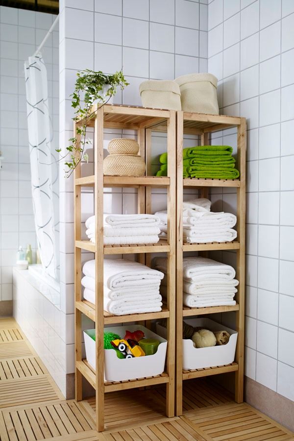 a wooden shelf filled with lots of white towels and other bathroom items next to a shower