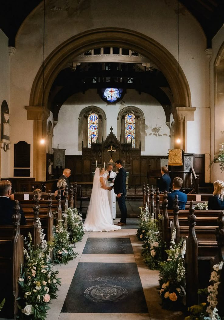 a bride and groom standing at the end of their wedding ceremony in front of pews