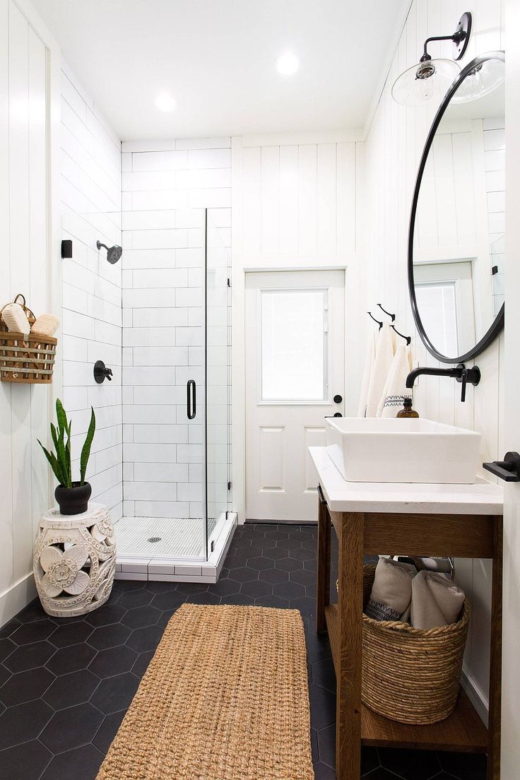 a bathroom with black and white tile flooring, a wooden sink vanity and a shower stall