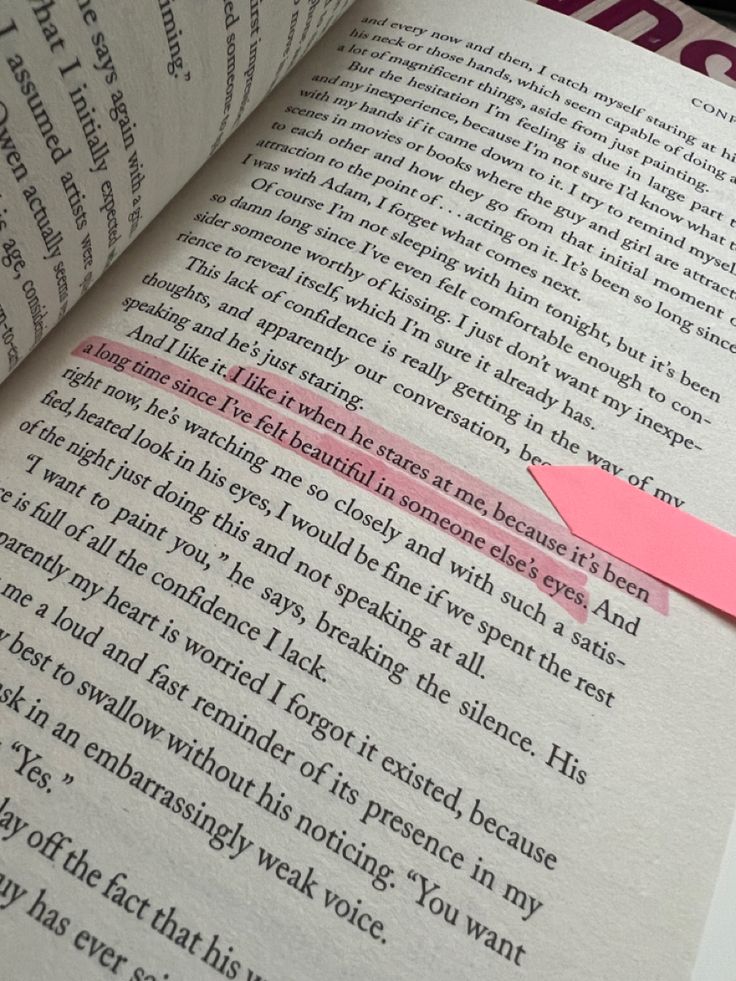 an open book with a pink piece of paper sticking out of it's middle