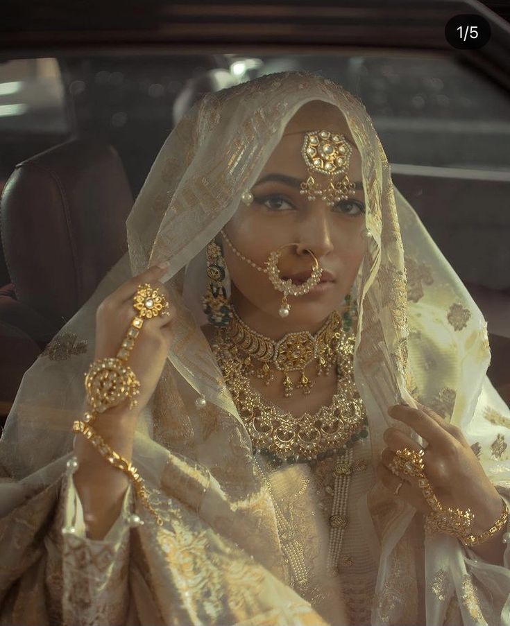 a woman in a car wearing gold jewelry and holding her hands up to her face