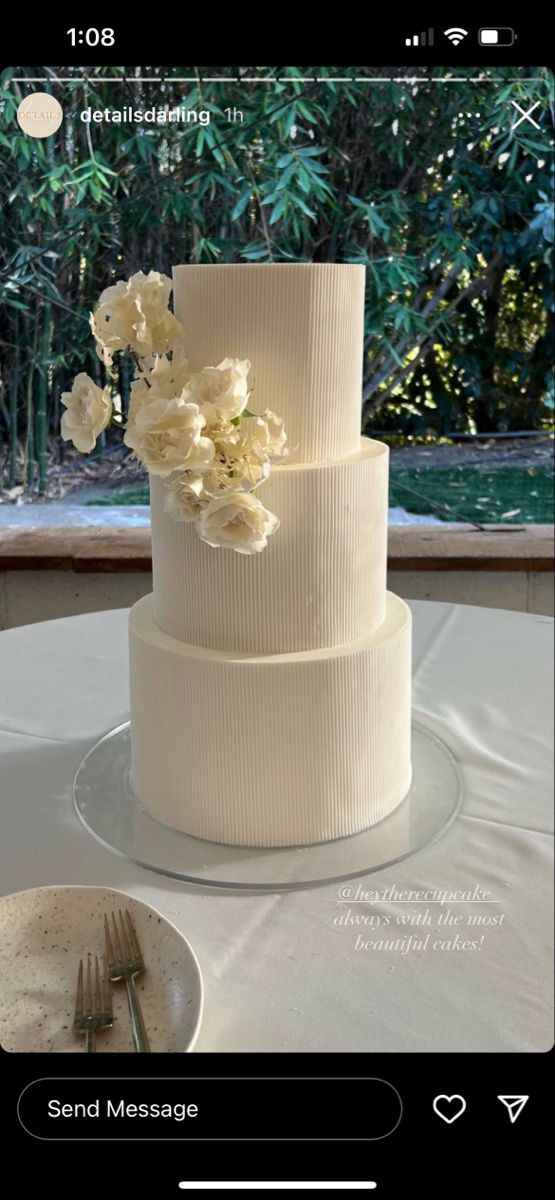 a white wedding cake sitting on top of a table next to a plate and fork